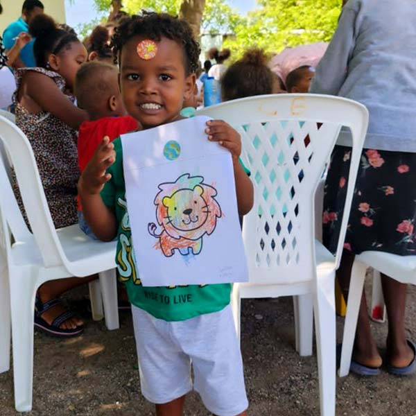Artista Junior mostrando su dibujo de león para bolso solidario
